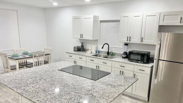 A modern kitchen with white cabinets, a granite countertop, and stainless steel appliances. - McAllen Home Pecan - Bicentennial (McAllen)