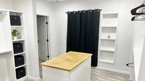 A compact, modern bathroom with a wooden vanity, white storage units, and a black shower curtain. - McAllen Home Pecan - Bicentennial (McAllen)
