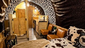 A cozy, cowhide-patterned bedroom with a wooden door leading to a kitchenette.