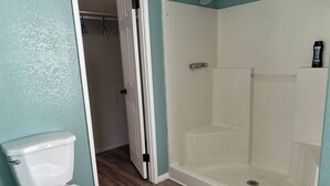 Ein Badezimmer mit Toilette, Dusche und einer Tür zu einem anderen Raum.