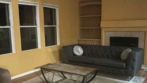 Ein Wohnzimmer mit einem dunkelgrauen Sofa, einem Holztisch und einem Kamin.