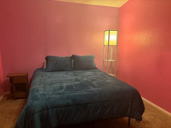 A bedroom with a bed, a nightstand, and a floor lamp.