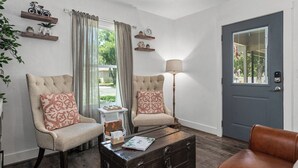 Una sala de estar con dos sillones, una mesa de centro y una puerta.