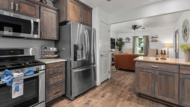 Una cocina moderna con electrodomésticos de acero inoxidable, armarios de madera y piso de madera.