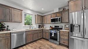 Una cocina con armarios de madera, electrodomésticos de acero inoxidable y un ventanal que proporciona luz natural.