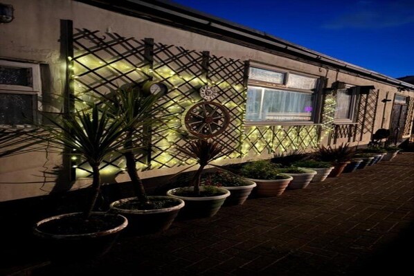 A building with a lattice facade and potted plants along the walkway.