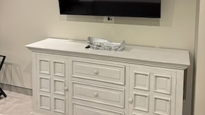 Ett vitt skåp med lådor och en platt-TV som är monterad på väggen.