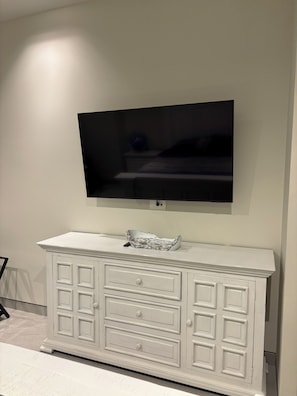 Ein weißes Schränkchen mit Schubladen und ein an der Wand befestigter Flachbildfernseher.