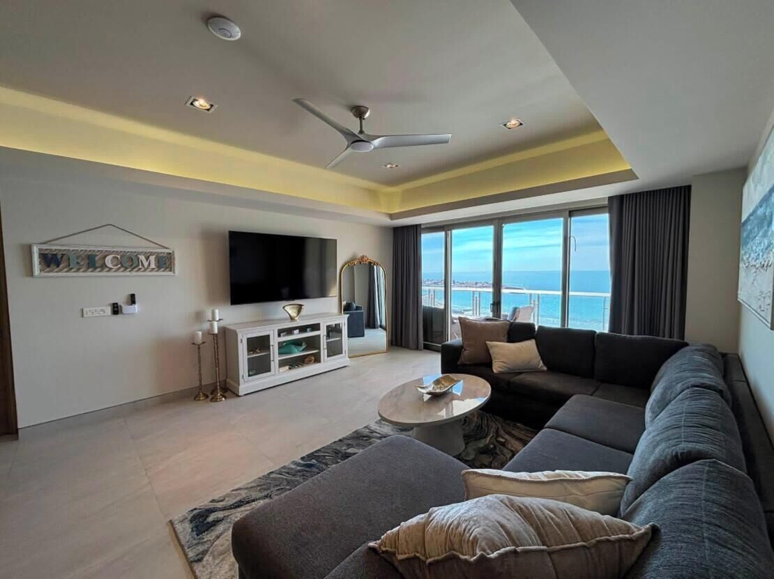 Una sala de estar moderna con un televisor de pantalla plana grande, un sofá, una mesa de centro y vistas al océano.