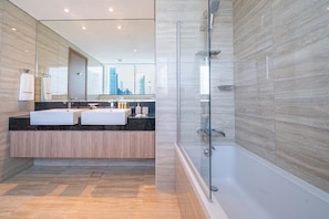 A modern bathroom with a glass-enclosed shower, a large mirror, and a city view.