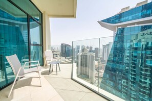 Un balcon doté d’une balustrade en verre, d’une chaise blanche et d’une petite table.