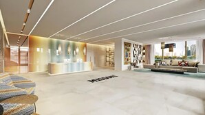 Een moderne lobby met een receptiebalie, zithoek en een trap.