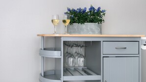 A grey kitchen cabinet with a wooden countertop, a sink, and a potted plant with blue flowers. - Golden Cottage | 2/1.5, Washer/Dryer, Full Kitchen (Fredericksburg)