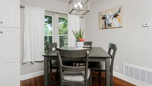 A dining area with a table, chairs, a chandelier, a potted plant, and a painting on the wall. - Golden Cottage | 2/1.5, Washer/Dryer, Full Kitchen (Fredericksburg)