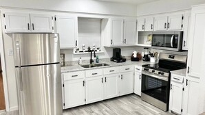 Une cuisine moderne avec des meubles blancs, des appareils en acier inoxydable et un plancher en bois gris.