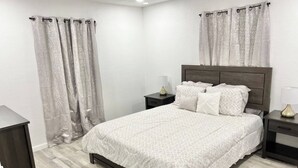 Une chambre à coucher avec un lit, des tables de chevet et des rideaux.
