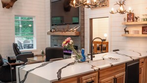 A modern kitchen with a large island, wooden cabinets, and a mounted elk head.