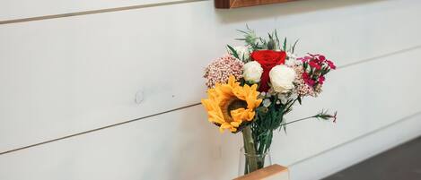 En trævæg med et billede af en bison i ramme, en vase med blomster og en tissueske på en mørk overflade.