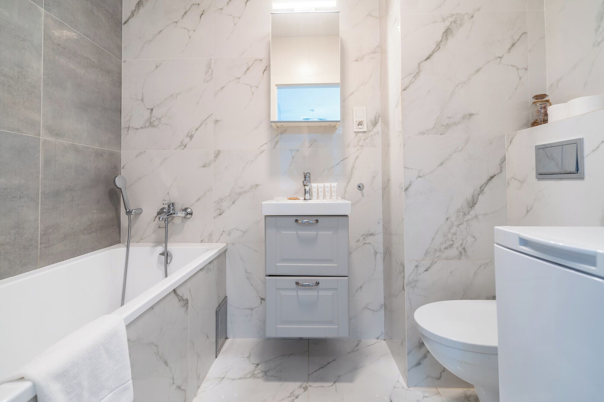 A bathroom with a bathtub, a sink with toiletries, and a toilet.