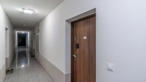 A hallway with a wooden door, a light switch, and a doorbell. - Park Śląski Charming Apartment (Katowice)