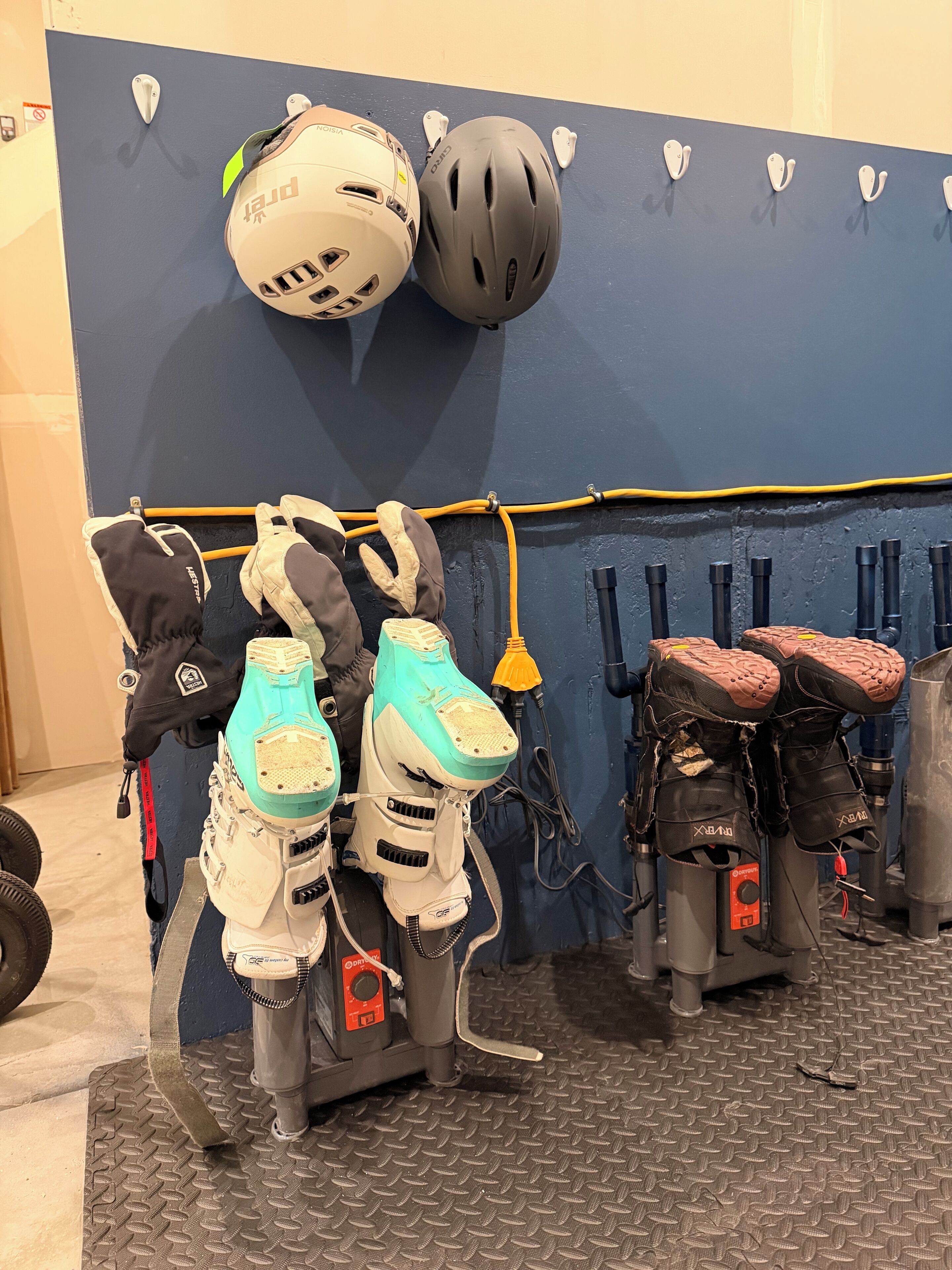 A wall-mounted rack with helmets, ski boots, and ski poles.