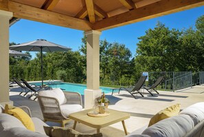 An outdoor pool area with lounge chairs, a table with a bottle and glasses, and a sign indicating a swimming pool. - Villa Arboreta (Istria - Rovinj) (Gržini)