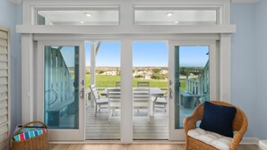 Una habitación con puerta de vidrio corredera que da a una terraza exterior con vista a la playa.
