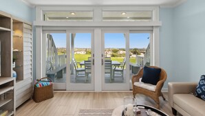 Amplia habitación con un gran ventanal corredero que da a un patio exterior con mesa y sillas.