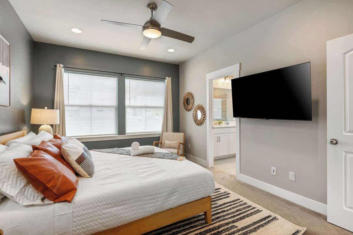 Una camera da letto con un letto, una ventola a soffitto, una televisione e una finestra.