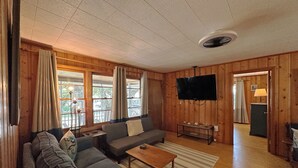 Un salon confortable avec un canapé, une table basse et un téléviseur à écran plat fixé au mur.