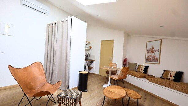 A modern living room with a sofa, chairs, a small table, and a dining area.