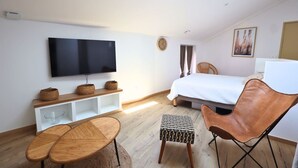 A modern bedroom with a flat-screen TV, a bed, a chair, and a small table.