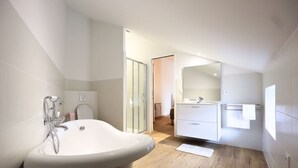 Ein modernes Badezimmer mit freistehender Badewanne, einem großen Spiegel und Holzboden.
