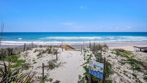 A beach with a wooden walkway leading to the water, surrounded by sand and sparse vegetation. - Florida Breeze |Pool & Jacuzzi| 2-min walk to BCH (St. Augustine)