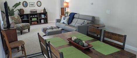 Una sala de estar con una mesa de comedor de madera, dos sofás, una estantería y un ventilador de techo.