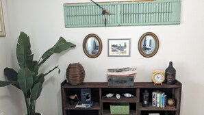 A wooden console table with various decorative items, a potted plant, and wall-mounted mirrors. - Marina Across the Street! Park your boat & Trailor here! (Ludington)