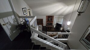 Een meerlaags interieur met een trap, woonkamer en een open haard.