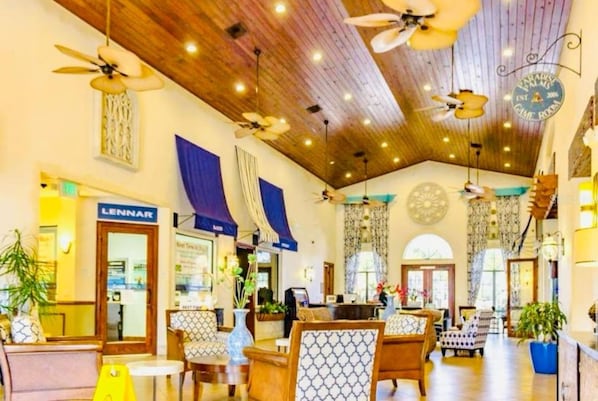 A spacious lobby with wooden ceiling beams, multiple ceiling fans, and a variety of seating arrangements including patterned chairs and sofas.