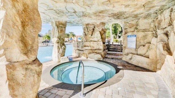 A pool area with a glass-bottomed hot tub, surrounded by rock formations and a pool.
