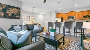A modern living room with a sofa, coffee table, and a dining area with chairs.