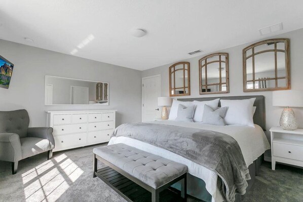 A bedroom with a bed, a bench, a dresser, and a chair.