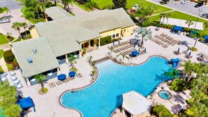 A resort with a large swimming pool, lounge areas, and a building with a tiled roof.