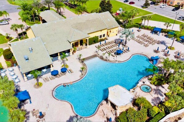 A resort with a large swimming pool, lounge areas, and a building with a tiled roof. - Amazing 4bdr House w Pool - PP (Kissimmee)