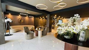 Un hall d’entrée moderne avec un comptoir d’accueil incurvé, un espace salon et un éclairage décoratif.