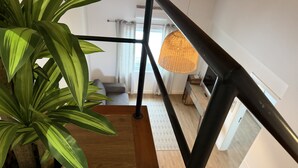 A staircase with a potted plant, a hanging light fixture, and a view into a living room. - AZORES PEDRA APARTMENTS - G (Fajã de Baixo)