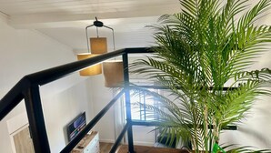 A staircase with a black railing, a potted plant, and a hanging light fixture.