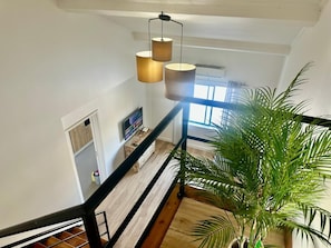 A staircase with a wooden handrail, a potted plant, and a TV on a stand. - AZORES STONE APARTMENTS H (Fajã de Baixo)
