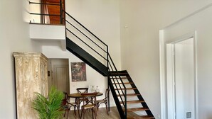 A modern interior with a staircase, wooden flooring, a dining area, and a sofa.