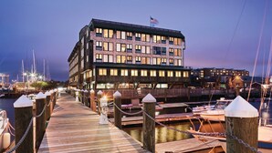 Un hotel sul lungomare con un molo di legno che conduce a barche ormeggiate.