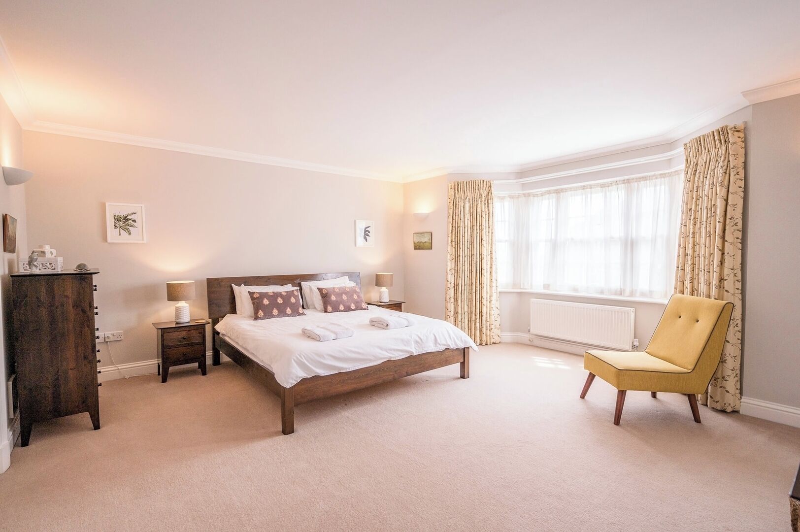 A bedroom with a large bed, bedside tables, a chair, and a window with curtains.